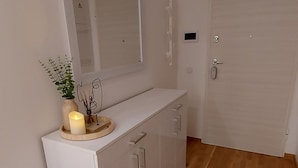 Un baño moderno y minimalista con tocador blanco, un espejo y una planta pequeña.