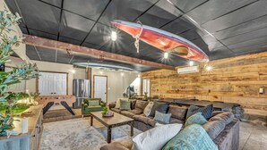 A cozy living room with a foosball table, comfortable sofas, and a wooden wall. - Private Estate | Sleeps 35 | 9 Bed 9.5 Bath | 2 Homes | Theater | Pond | Sport Court | Hot Tub | Sauna (Ravenna)