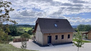 A wooden barn-style building with a sloped roof, a small porch, and a gravel driveway. - Modern house in the heart of Green Périgord with pets allowed (Preyssac-d'Excideuil)