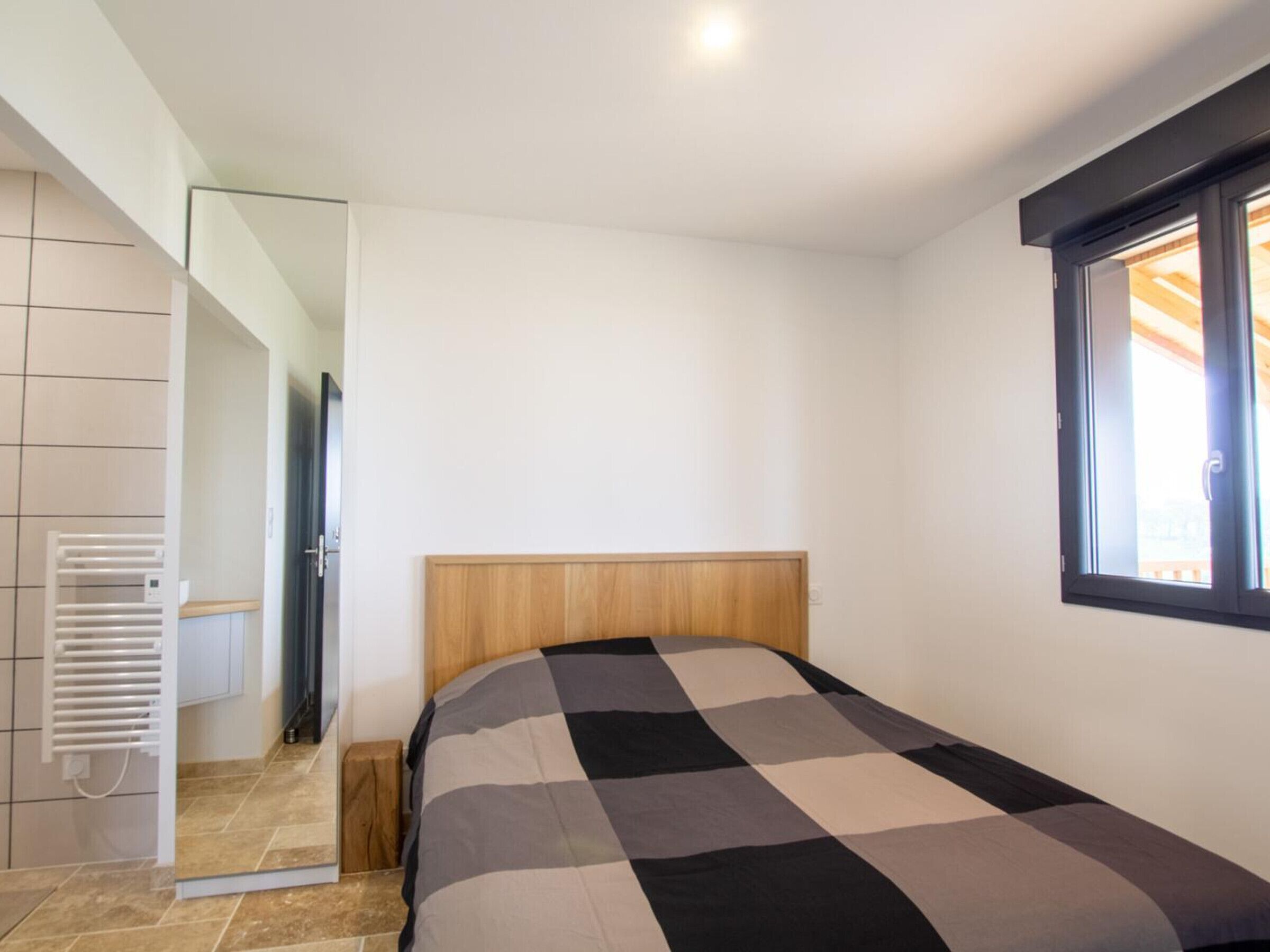 Ein Schlafzimmer mit einem Bett, einem Fenster und einer Tür zu einem Badezimmer.