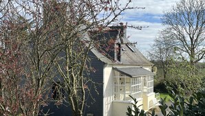 Une maison à l’extérieur sombre, avec un porche blanc et une cheminée bien visible.