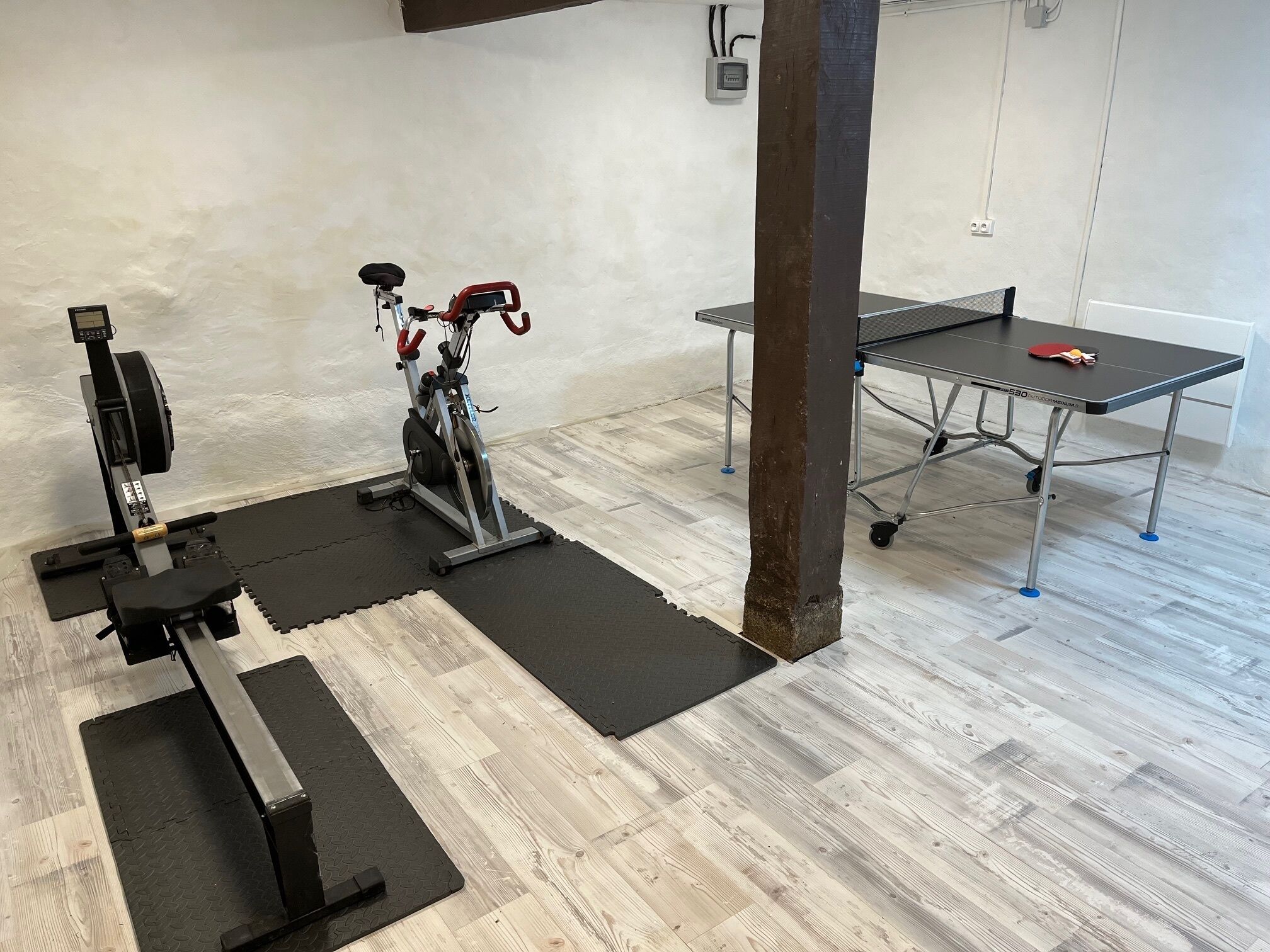 Een sportschool met fitnessapparatuur, een tafel en een stoel.