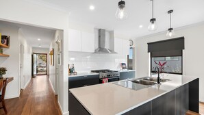 A modern kitchen with a central island, stainless steel appliances, and pendant lighting. - Porta Rossa (Anglesea)
