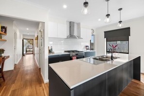 Een moderne keuken met een centraal eiland, roestvrijstalen apparatuur en hanglampen.