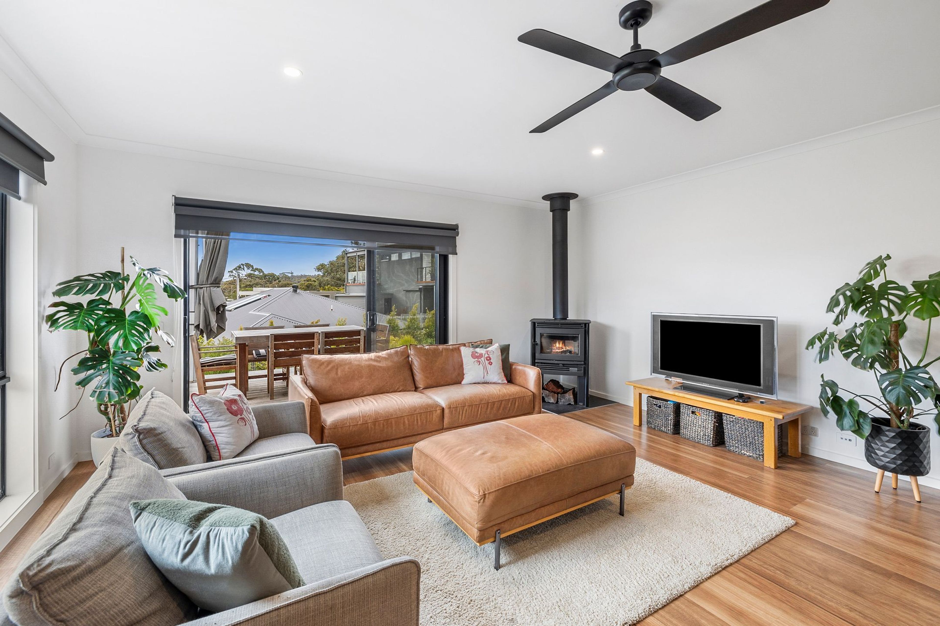 A modern living room with a sofa, ottoman, TV, and a fireplace.