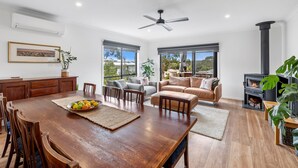 A spacious living area with a dining table, sofas, and a fireplace. - Porta Rossa (Anglesea)