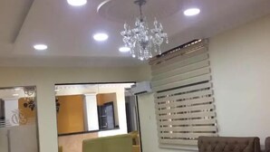 A conference room with a long table, chairs, a chandelier, and a window with blinds. - TD RESIDENCE INN (Ijebu Ode)
