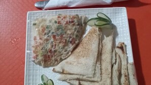 A plate with a rolled omelette and several slices of toast on a white plate, placed on a red tray. - TD RESIDENCE INN (Ijebu Ode)