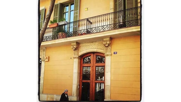 A building with a wooden door and a balcony with a wrought iron railing. - Cozy attic penthouse in center of BCN. Sun, views, quiet... close to main spots. (Barcelona)