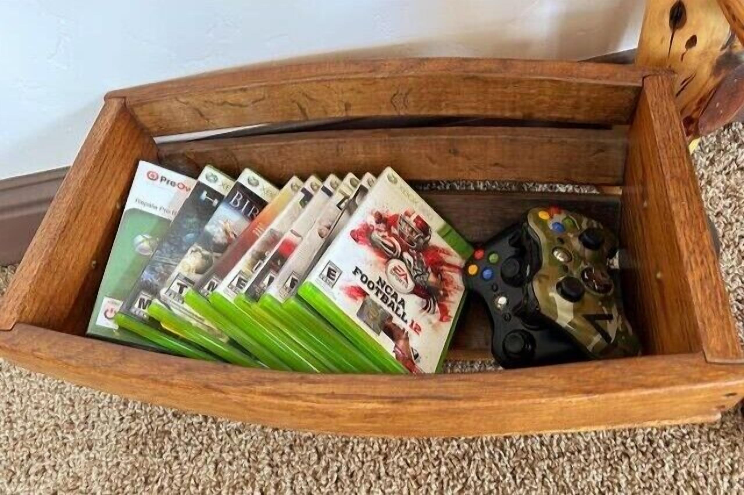 A wooden tray containing video game cases and a gaming controller.
