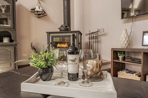 Un accogliente soggiorno con camino, un vassoio con una bottiglia di vino, bicchieri e una pianta in vaso.