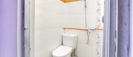 A small, compact bathroom with a toilet, a shower, and a tiled floor.