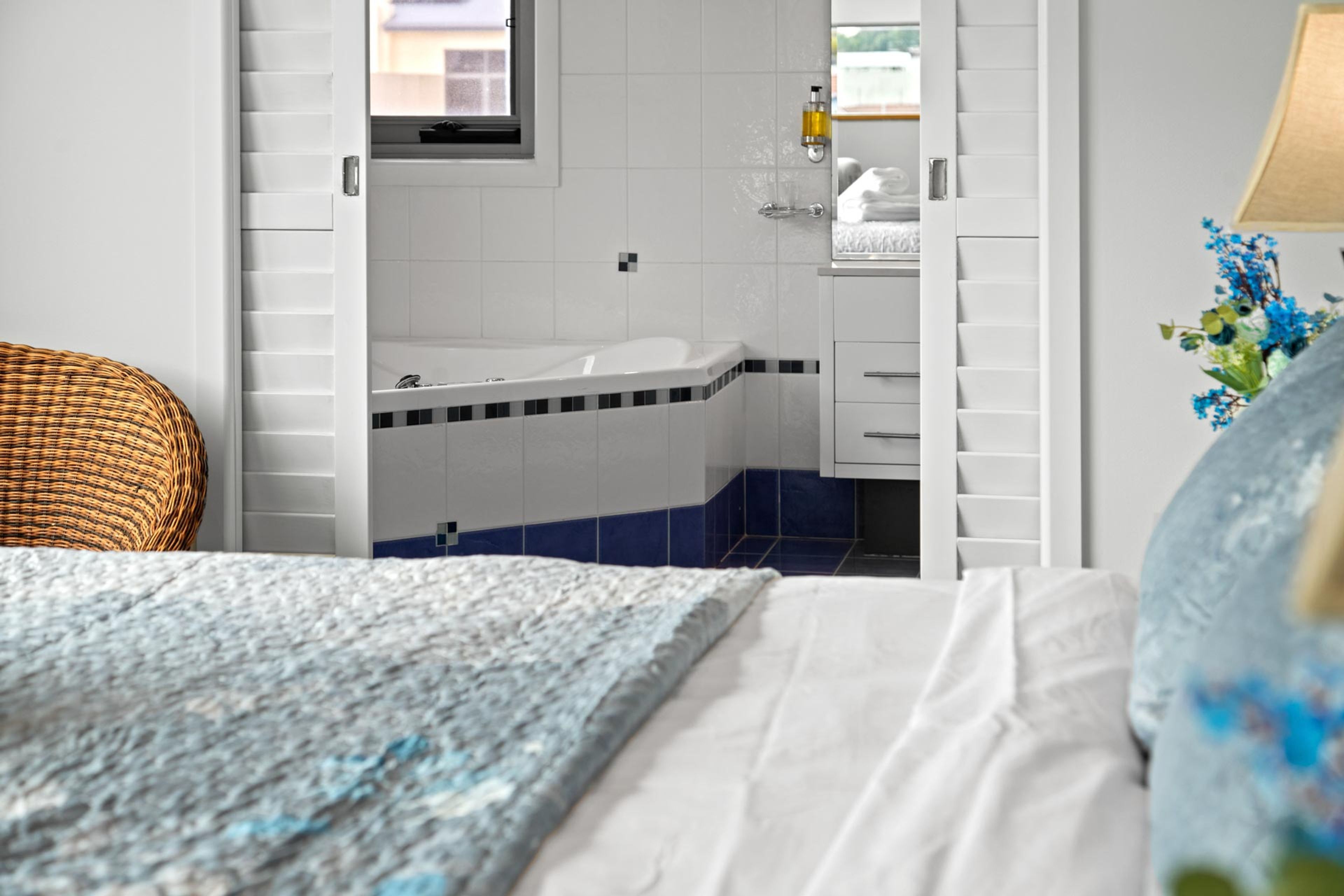 A bedroom with a bed, a bathroom with a bathtub, and a window.