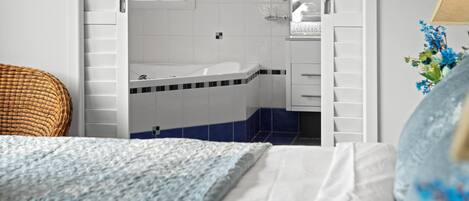 A bedroom with a bed, a bathroom with a bathtub, and a window.