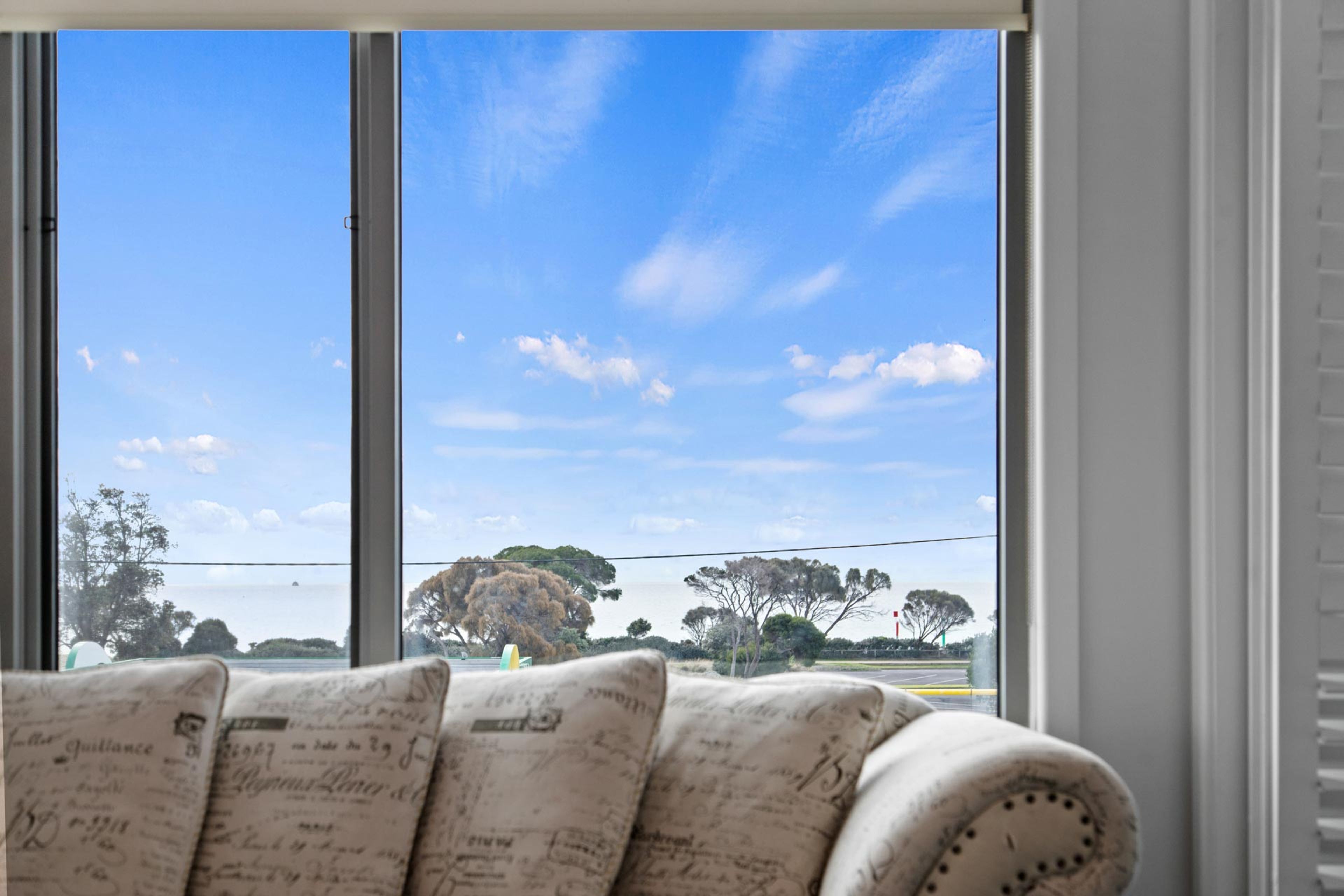 A room with a large window offering a view of a clear sky and distant trees.