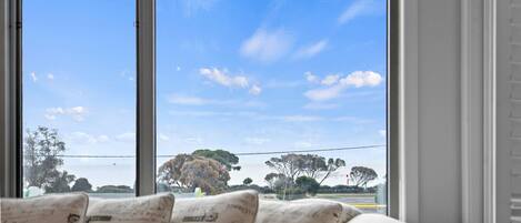 A room with a large window offering a view of a clear sky and distant trees.