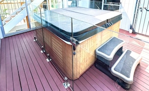A wooden outdoor seating area with a glass-top table and metal legs.