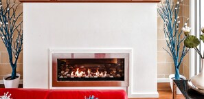 Een modern vormgegeven haard, omlijst door decoratieve takken met witte versieringen.