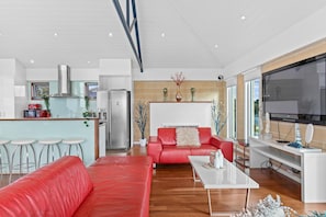 A modern living space with a kitchen, a red sofa, a coffee table, and a TV.