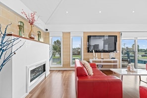 A modern living room with a fireplace, red sofa, and a large TV.
