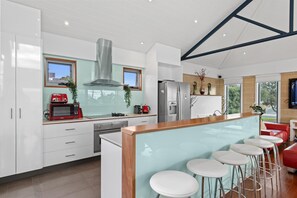 Una cocina moderna con muebles blancos, electrodomésticos de acero inoxidable y una isla central con taburetes de bar.