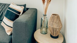 A living room with a grey sofa, a vase with pampas grass, and a woven lamp on a round wooden table. - Beach House Clim, 100m Plage, sur le Port. Paisible et Calme (Frontignan)