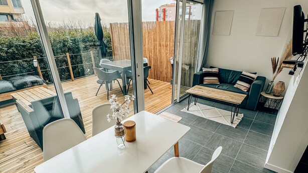 A modern living space with a dining area, a sofa, and a TV. - Beach House Clim, 100m Plage, sur le Port. Paisible et Calme (Frontignan)