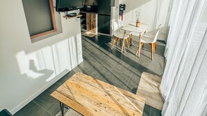 A modern living room with a wooden coffee table, a TV, and a kitchen area in the background. - Beach House Clim, 100m Plage, sur le Port. Paisible et Calme (Frontignan)