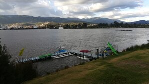 Vista de un lago con un muelle, barcos y un paisaje urbano distante.