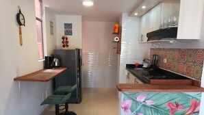 Una cocina compacta con encimera de madera, un refrigerador y un salpicadero colorido.
