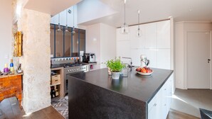 A modern kitchen with a central island, built-in appliances, and pendant lighting. - Soulful Fusion, by Veeve (Paris)