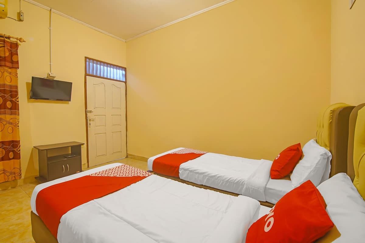 Ein Hotelzimmer mit zwei Betten, einem Fernseher, einem Kleiderschrank und einer Tür.