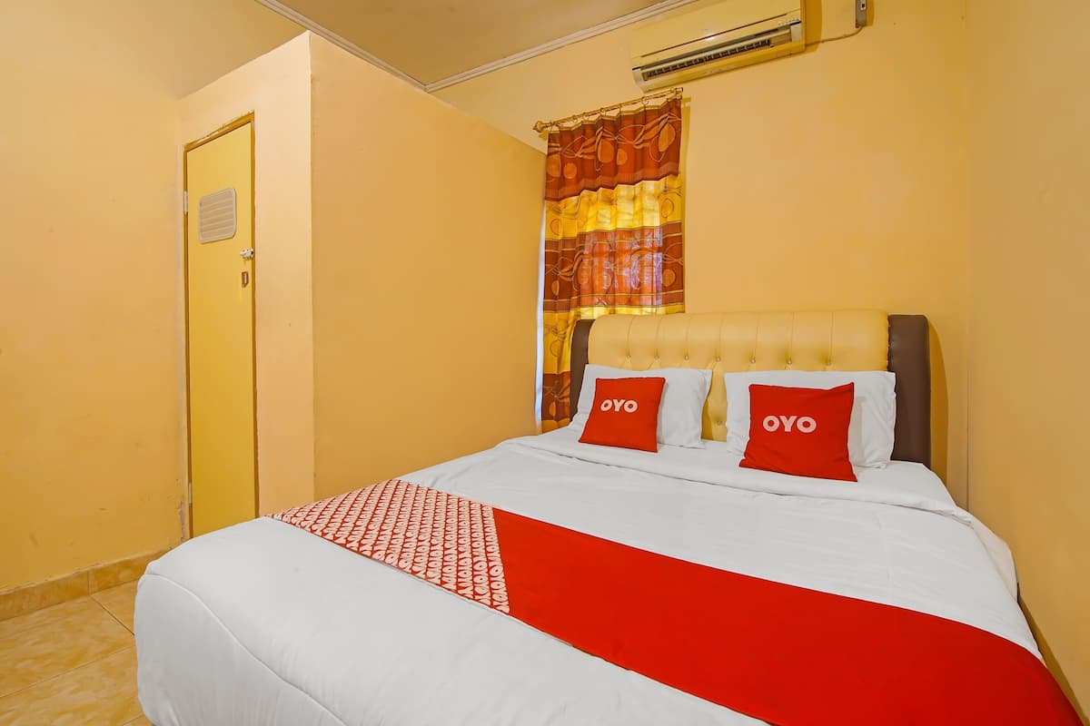 Ein Hotelzimmer mit Bett, Tür, Klimaanlage und Vorhang.