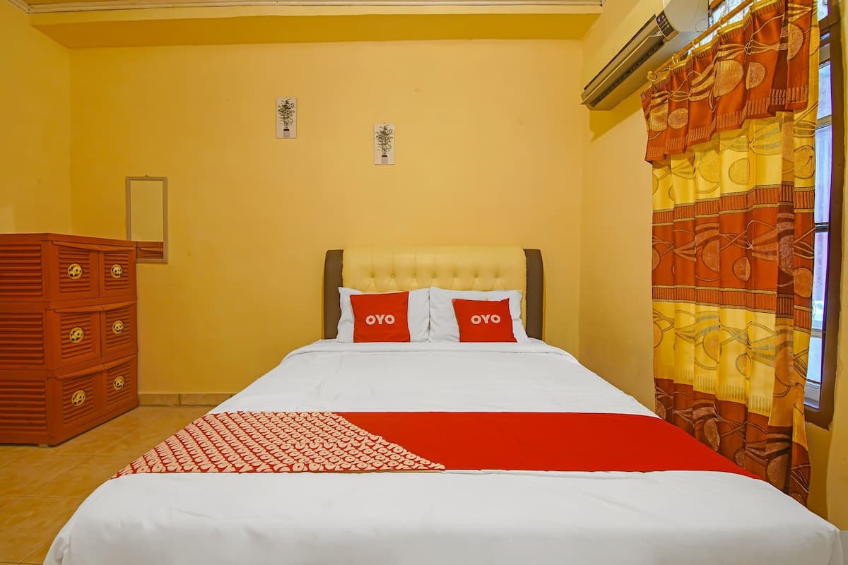 Ein Hotelzimmer mit Bett, Kommode und einem Fenster mit Vorhängen.