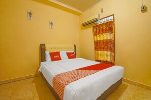 Une chambre d’hôtel avec un lit, une fenêtre avec un rideau, un appareil de climatisation et un petit élément de décoration murale.