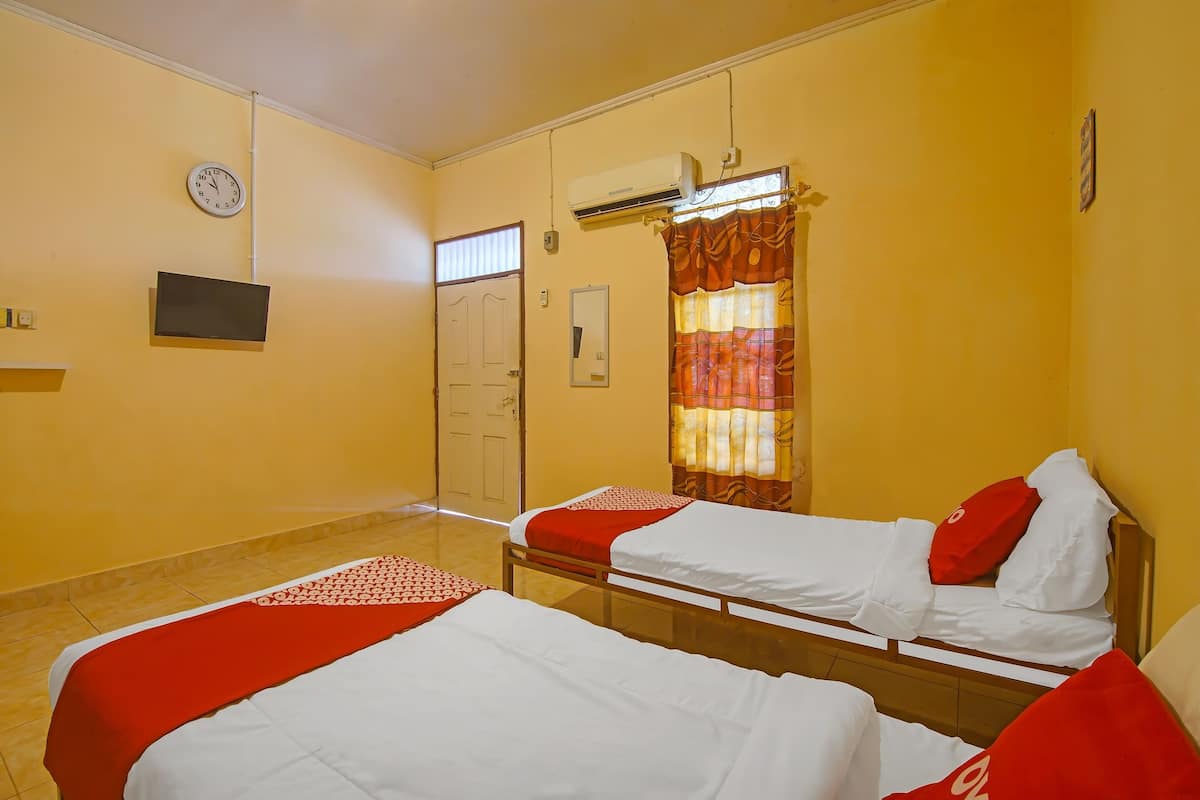 Ein Hotelzimmer mit zwei Einzelbetten, einer Uhr, einer Klimaanlage und einem Fenster mit Vorhängen.