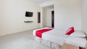 A hotel room with a bed, a TV mounted on the wall, and a wooden side table. - OYO 3343 Sunrise Hotel (Banjarbaru)
