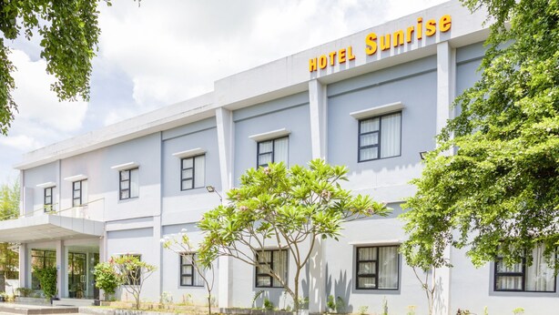 A hotel named "Hotel Sunrise" with a modern facade, multiple windows, and a paved entrance area. - OYO 3343 Sunrise Hotel (Banjarbaru)