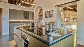 Una cocina moderna con una isla central, electrodomésticos integrados y una pared de piedra rústica.