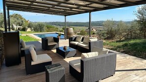 Un patio al aire libre con mobiliario de mimbre, una piscina y vistas al campo.