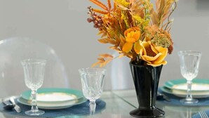 A dining table with a vase of flowers, clear glassware, and blue plates. - Sunny Apartment | 2 Bedrooms, Balcony and Air Conditioning (Warszawa)