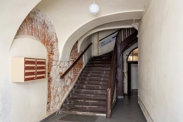 Eine Treppe mit hölzernem Geländer, einem Briefkasten und einem Schild für eine Kunstgalerie.