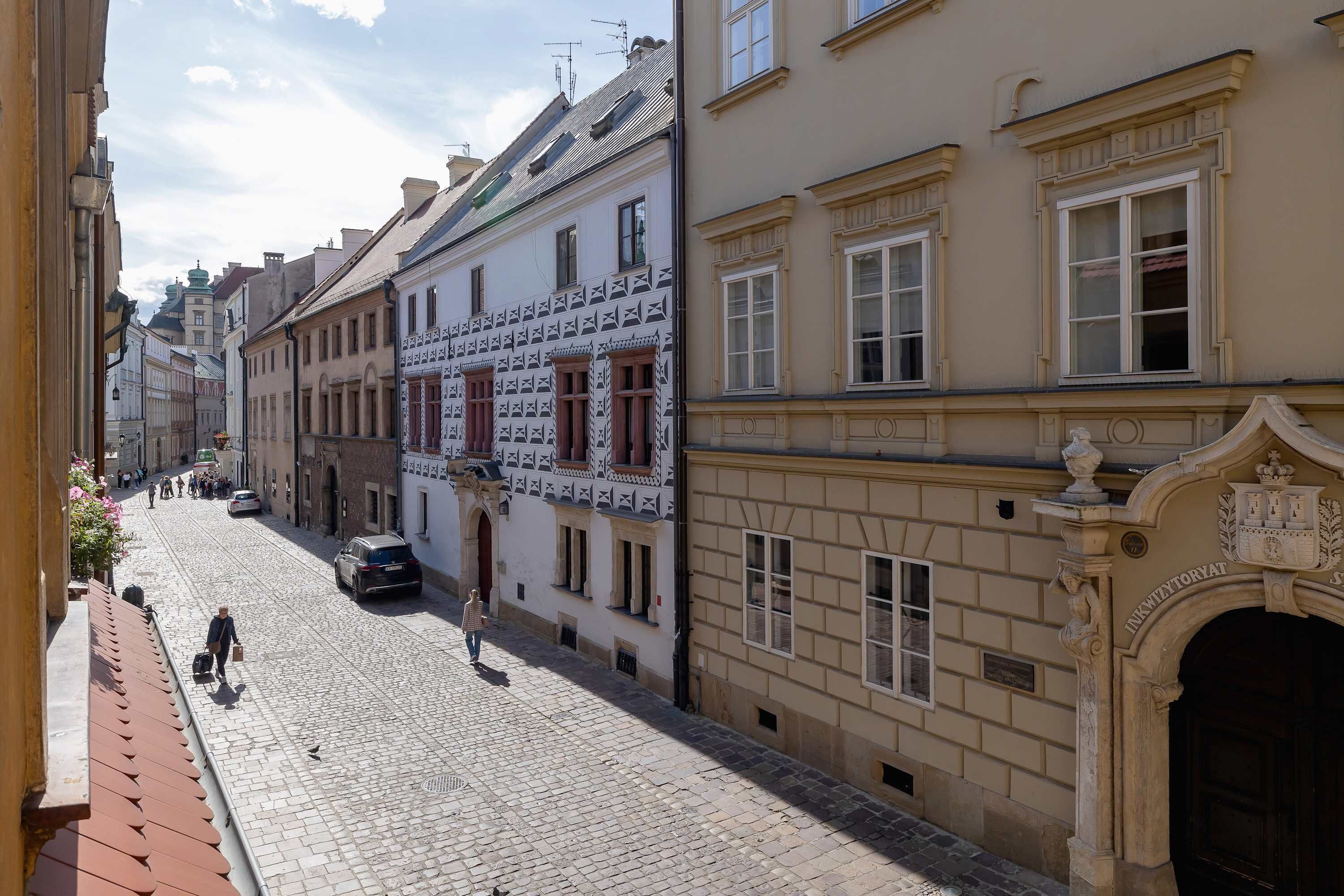 En kullerstensgata kantad av historiska byggnader, med utsmyckade fasader och traditionell arkitektur.