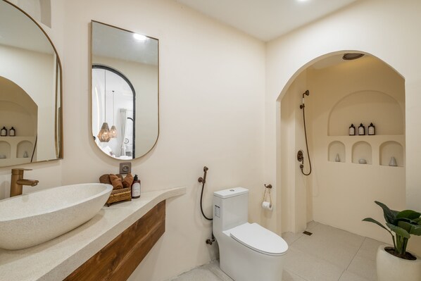 Une salle de bain moderne avec un grand lavabo sur pied, des toilettes et un espace douche.