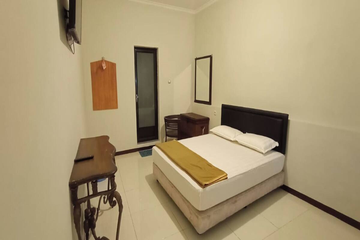 Un dormitorio con cama, mesita de noche y escritorio.