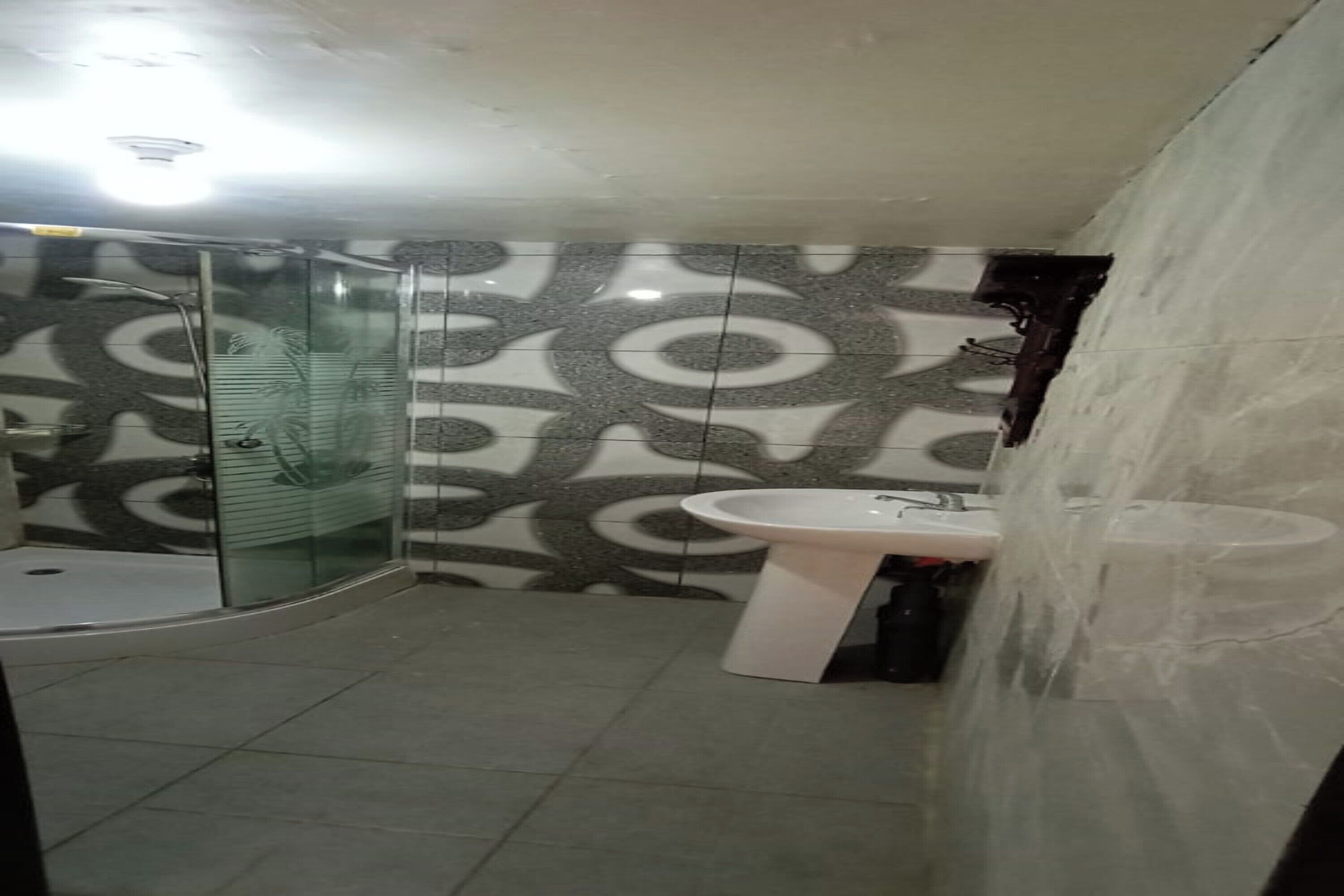 A bathroom with a glass shower enclosure, a white sink, and patterned walls.