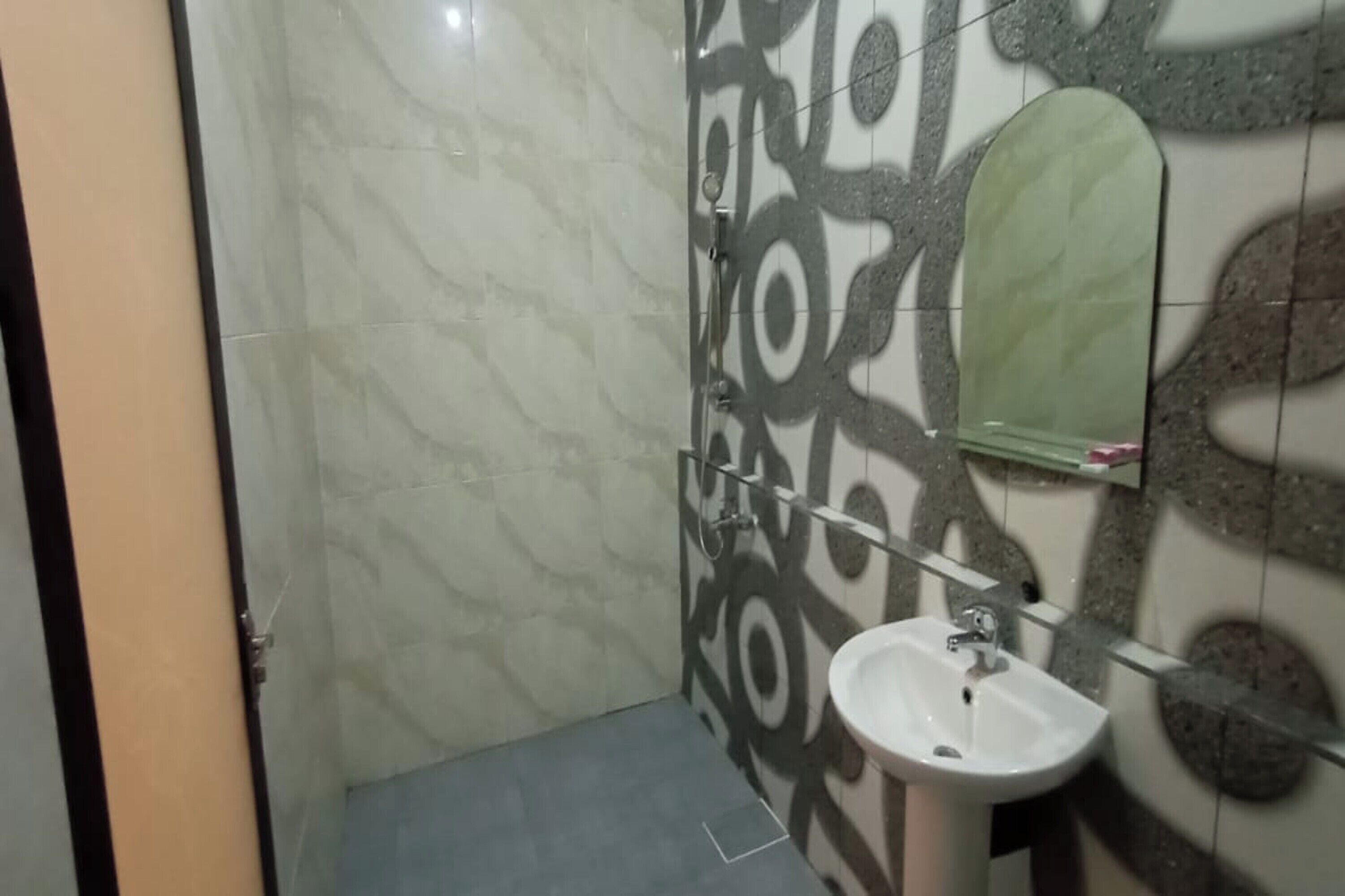 A bathroom with a white sink, a mirror, and patterned tiles on the walls.