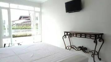 Un dormitorio con cama, televisor montado en la pared y ventana con vistas al exterior.