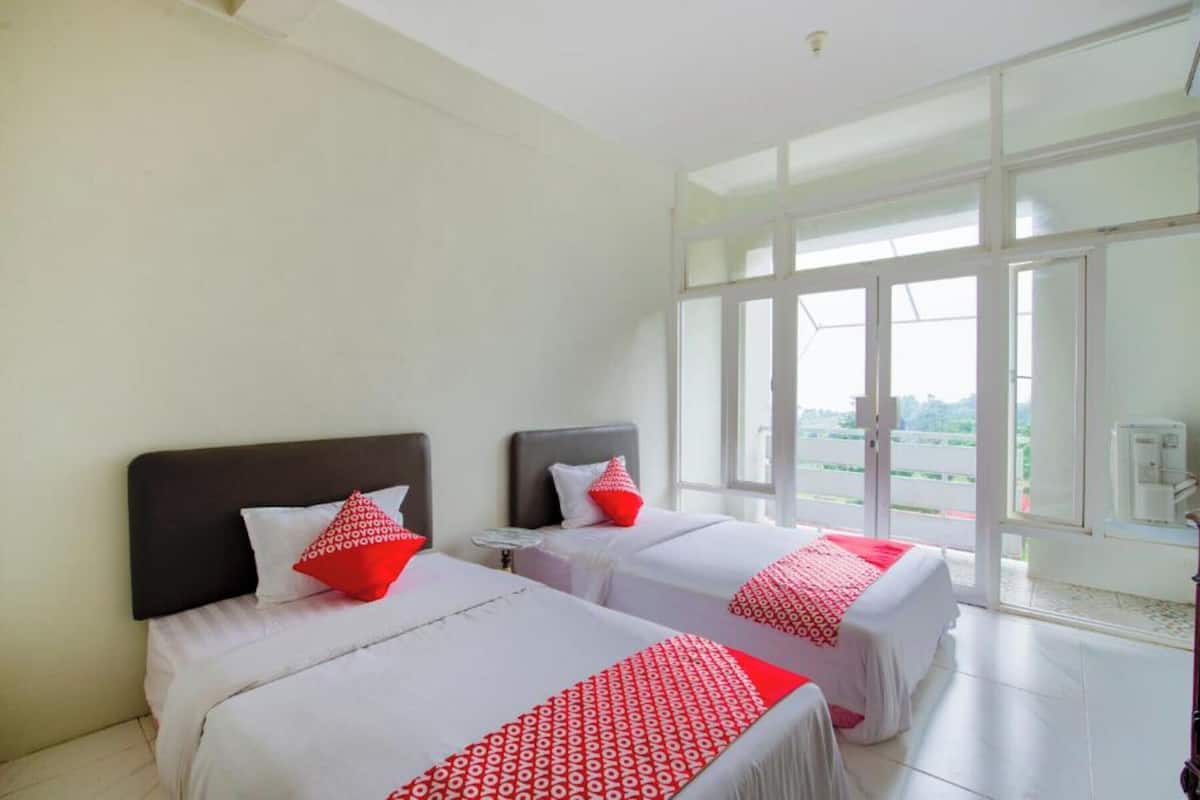 Habitación de hotel con dos camas, ventanas amplias y vistas al exterior.