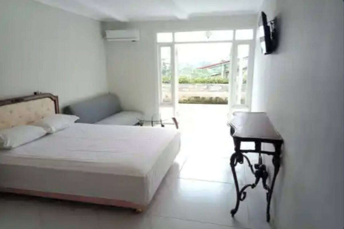 Un dormitorio con cama, una mesita de noche y vistas al exterior a través de una ventana.